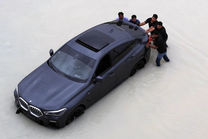 Người dân Dubai hì hục đẩy một chiếc BMW X6 khác. Chia sẻ nhiều công nghệ với X5, BMW X6 mang phong cách thể thao coupe đặc trưng.