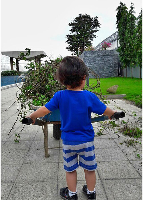 Nữ ca sĩ “Đường cong” khoe khoảnh khắc cậu quý tử phụ giúp mẹ đổ cỏ dại trong sân vườn. Ảnh: FBNV