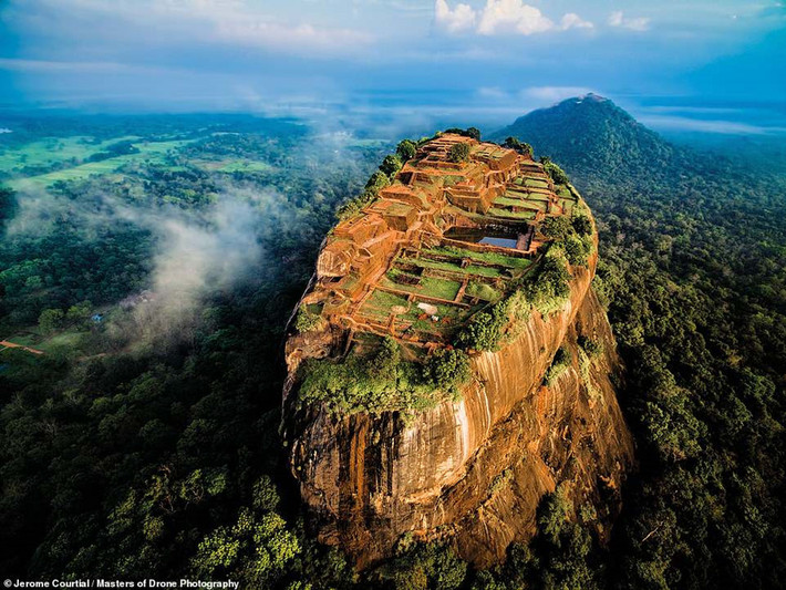 Sigiriya ở Sri Lanka là phế tích cung điện cổ được xây trên núi đá cao 370 m dưới triều đại vua Kassapa I (477-495). Jerome Courtial, tác giả của bức ảnh, cho biết anh gặp khó khăn khi tìm chỗ bay fly cam. Bao quanh Sigiriya là khu rừng rậm với nhiều loài động vật hoang dã sinh sống. "Tôi khá may mắn khi có thể bắt ánh sáng đẹp. Những đám mây nhỏ bên trái khiến cho bức hình trở nên dễ chịu hơn", anh nói.