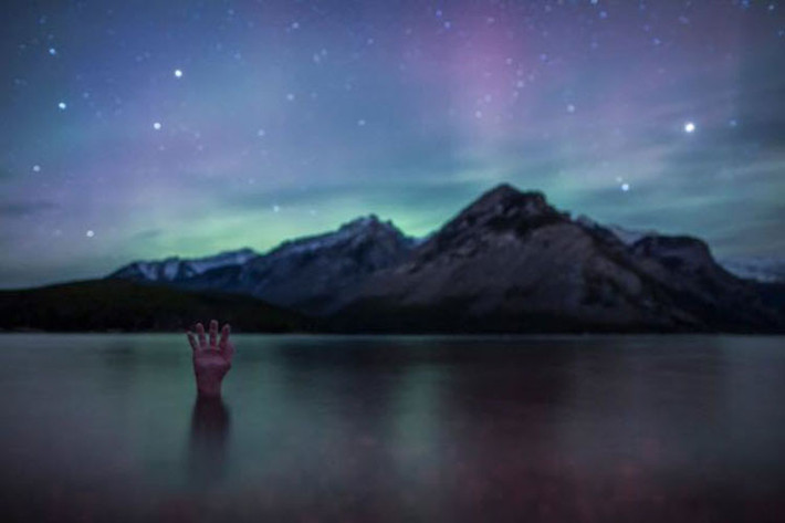 Bàn tay nhô lên từ dưới mặt nước trên hồ Minnewanka trong vườn quốc Banff, Canada.