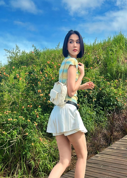 Ngọc Trinh diện chân váy ngắn xếp ly kết hợp áo phông. Cô đeo balo, đi dép sandal.