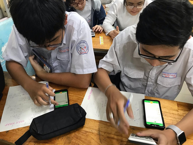 Học sinh TP.HCM làm bài kiểm tra trên smartphone: THPT Trần Hữu Trang và THPT Nguyễn Du là 2 trường thí điểm cho học sinh làm bài kiểm tra qua ứng dụng công nghệ tại TP.HCM. Không đề hay phiếu trả lời, học sinh làm bài kiểm tra trên điện thoại di động hoặc máy tính có kết nối mạng Wi-Fi của trường. Ứng dụng sẽ chấm điểm, tự động lưu vào sổ cho giáo viên và gửi về phụ huynh bằng email hoặc tin nhắn điện thoại. Ảnh: H.N.