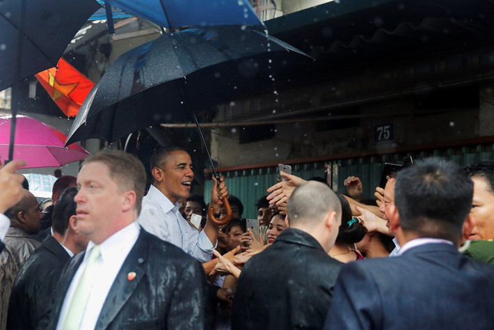 Trong cơn mưa trưa 24/5, ông Obama dừng chân ở cổng làng Mễ Trì Thượng (Nam Từ Liêm, Hà Nội), nói chuyện với một chủ quán trà đá và người dân trước khi bay vào TP HCM. Sự thân thiện của ông Obama khiến người dân địa phương thích thú. Nhiều người bày tỏ sự hạnh phúc khi được bắt tay vị tổng thống Mỹ. Ảnh: Reuters