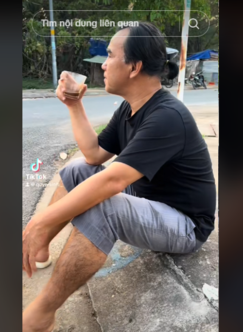 Ông bố ngồi bệt uống cà phê trong một lần đi quay. Ảnh: TikTok Quyền Linh.