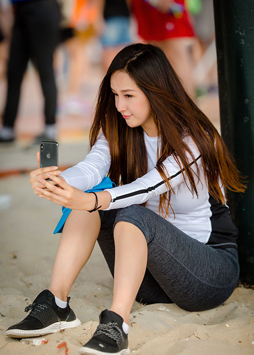 Sau khi chạy bộ, Mai Phương Thúy ngồi bệt trên cát để nghỉ ngơi.