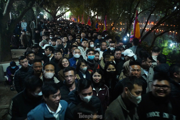 Lối vào sân đền cũng kín người. Lúc này, mưa bắt đầu đổ xuống nhưng không ngăn được sự thành tâm của người dân hướng về Đức Thánh Trần.