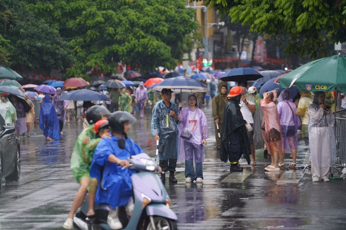 Chiều 1/9, bất chấp trời đổ mưa, dòng người vẫn ùn ùn đổ về khu vực đường Hùng Vương, Nguyễn Thái Học chờ xem diễu binh, diễu hành vào sáng này 2/9.