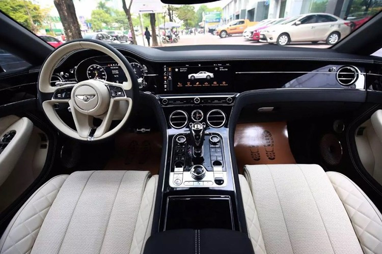 Das Cockpit des Bentley Continental GT V8 Super-Luxus-Coupés ist in Schwarz und Weiß gehalten. Der Innenraum ist außerdem mit einem großen zentralen Touchscreen ausgestattet, der dezent im holzgetäfelten Armaturenbrett versteckt ist. Darunter befindet sich eine mechanische Uhr, genau in der Mitte platziert, und ein großer elektronischer Schalthebel. 3.jpg