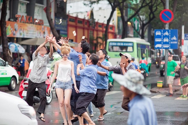 Cô gái mặc áo hai dây, quần soóc khoe chân dài, đeo kính mát cầm một cọc tiền đi trên vỉa hè, đến mép đường thì vung tiền, để đám người đàn ông xung quanh xúm lại, chạy theo lụm nhặt. Cảnh tượng khiến nhiều người đi đường phải "há hốc mồm" kinh ngạc.