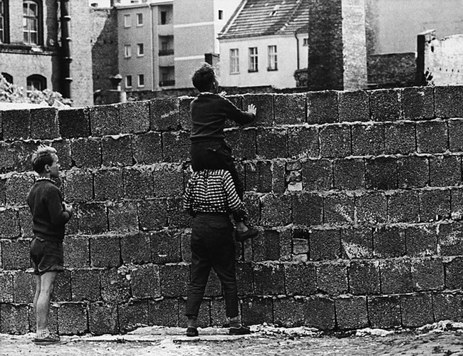 Bức tường Berlin ngăn cách Đông Đức XHCN và Tây Đức TBCN. Ảnh: các cậu bé đang công kênh nhau trên đường Liesen ở Wedding, Tây Berlin để nhìn qua bước tường về phía Đông, năm 1961.