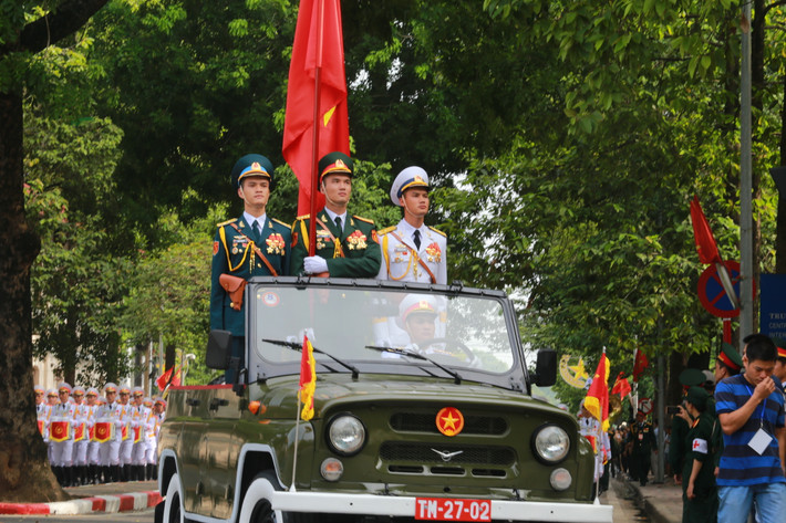 Tổ rước quân kỳ đi sau xe chở Trung tướng Võ Văn Tuấn dẫn đầu đội hình diễu binh, diễu hành bắt đầu tiến vào các con phố chật kín người xem.