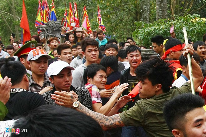 Một thanh niên xăm trổ đầy cánh tay vụt liên tiếp đội bảo vệ kiệu sau khi bị ngăn cản cướp lộc.
