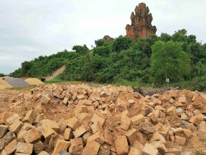 Trong quá trình thi công xây dựng, tu bổ, tôn tạo di tích Tháp Bánh Ít, chủ đầu tư và nhà thầu thi công phải dùng thủ công, máy đầm đất cầm tay san gạt sân phía trước tháp chính thì lại đưa xe cơ giới máy múc vào “oanh tạc” di tích, không đúng hồ sơ thiết kế được thẩm định.(Ảnh: Tài nguyên và Môi trường).