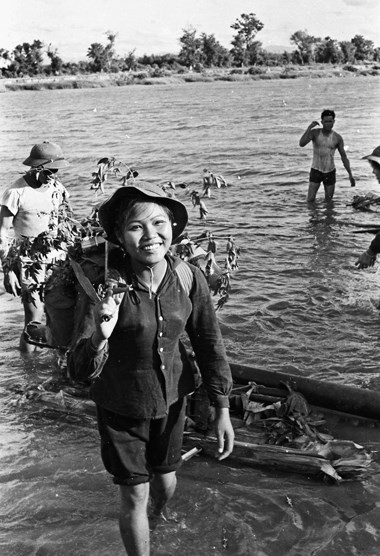 Bức ảnh "chiến sĩ giao liên" với nụ cười tươi của o du kích đang băng rừng vượt sông làm nhiệm vụ.