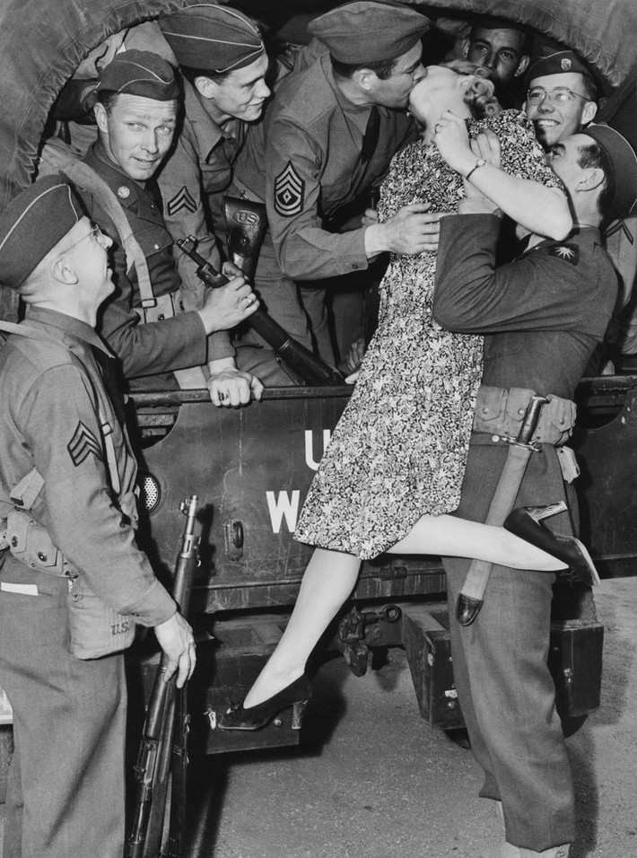 Nữ diễn viên Martha O’driscoll hôn tạm biệt một người lính ở Los Angeles, Mỹ năm 1941 với sự giúp đỡ của những người đồng đội.
