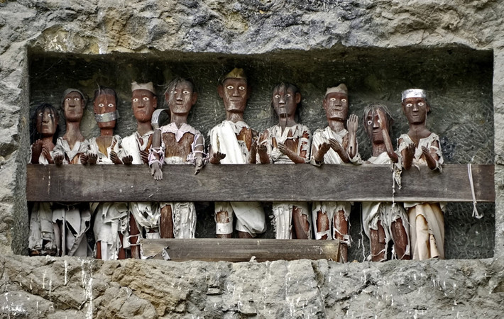 Hình nộm người chết (Tau Tau): Cũng là một truyền thống từ Tana Toraja, Tau Tau là hình nộm chạm khắc từ gỗ hoặc tre đại diện cho người đã chết, thường giống người đó và có thể tìm thấy gần mộ. Người Toraja tin rằng linh hồn của người chết sẽ tiếp tục sống qua Tau Tau và phục vụ như người bảo vệ ngôi mộ. Ảnh: Indoindians.