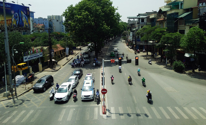 Nhiều người trốn nắng dưới bóng cây xanh trên đường Láng trong lúc chờ đợi đèn đỏ.