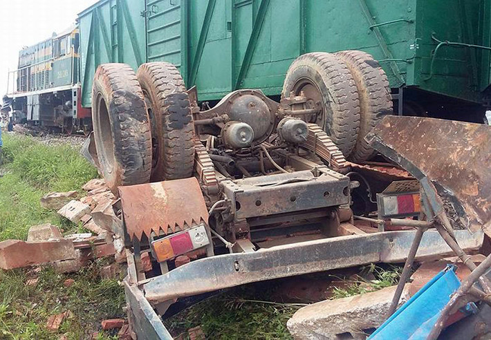 Chiếc xe tải chở gạch bị tàu húc văng ra phía bờ ruộng, nằm phơi bụng lên trời.
