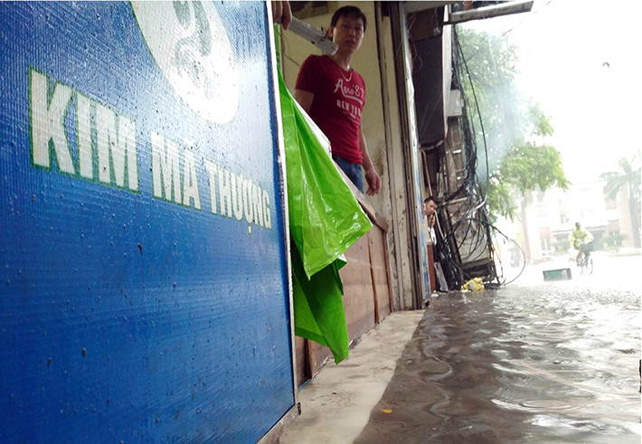 Mực nước càng lúc càng dâng cao trên phố Phố Kim Mã Thượng (phường Cống Vị, quận Ba Đình, TP Hà Nội), người dân phải sử dụng các tấm ván để che chắn.
