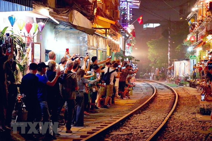 Khi đoàn tàu xuất hiện cũng là lúc tất cả camera, máy ảnh, điện thoại được sử dụng hết công suất, du khách reo hò vui vẻ khiến cho bầu không khí nơi xóm nhỏ trở nên ồn ã đến lạ thường. (Ảnh: Vi Thương - Hải Yến/TTXVN).