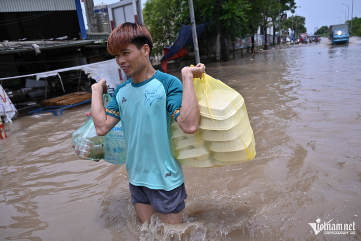 Anh Lâm Hải Dương (34 tuổi) đi mua đồ ăn trưa cho cả xưởng bị ngập gần đó. "Mấy ngày nay công nhân chúng tôi liên tục phải tìm kiếm, thu vớt đồ đạc trong kho bị ngập. Tranh thủ nghỉ trưa tôi lội nước đi mua đồ ăn giúp mọi người để chiều dọn dẹp tiếp", anh kể.