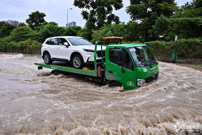 Một xe cứu hộ chở chiếc ô tô còn rất mới để vượt qua đoạn ngập sâu.