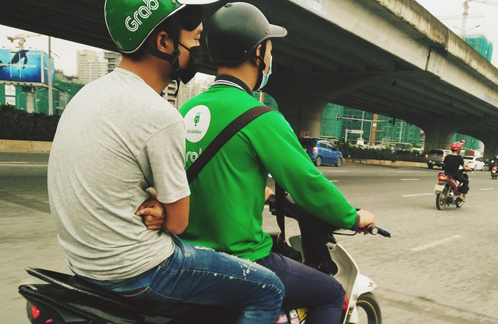 Một nam thanh niên cảm thấy lạnh, ngồi sau xe máy hay tay khoanh vào nhau suýt xoa.