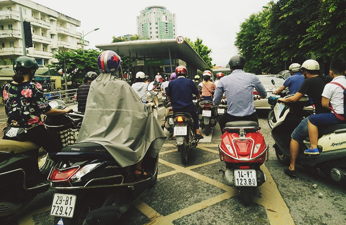 Một số người không mang theo áo khoác đành phải mặc áo mưa để giữ ấm cho cơ thể khi di chuyển trên đường Hà Nội.