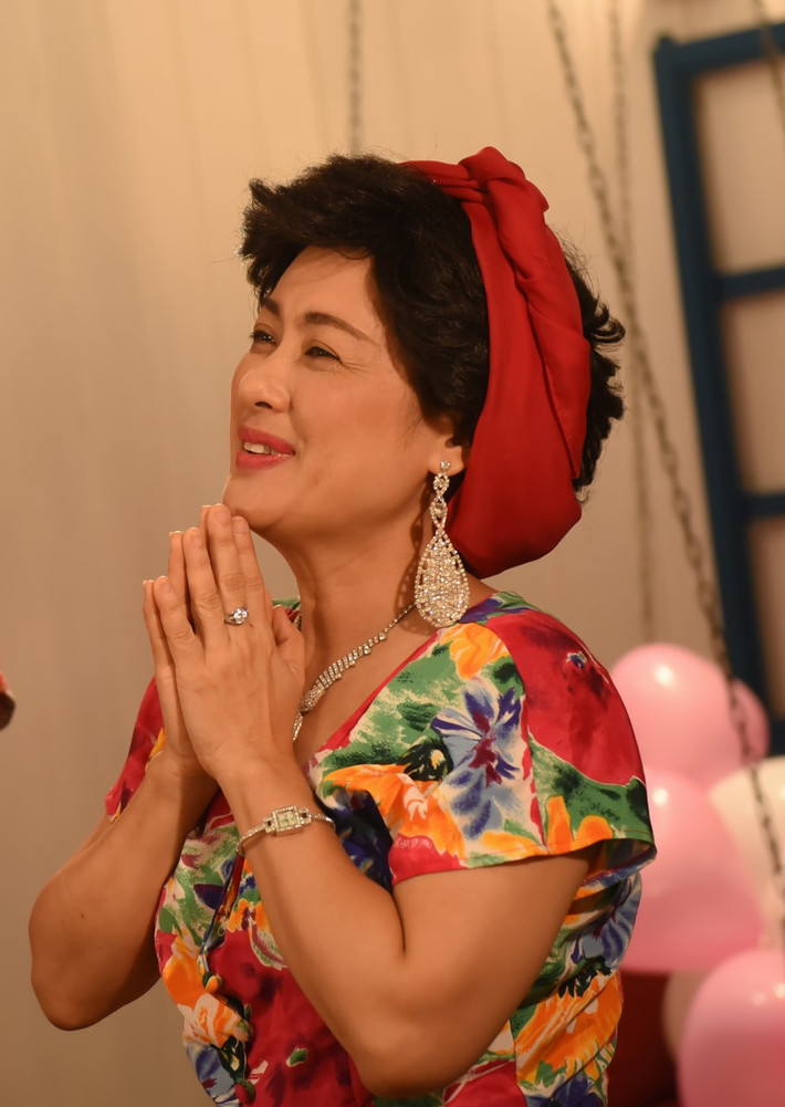 Bà Sáu diện váy hoa cam nổi bật và chiếc mũ “ton sur ton”.