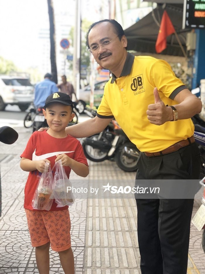 Một trong những hình ảnh có thể nói rất đẹp trong ngày bầu Thắng bán cà phê là hai mẹ con đứng xếp hàng gần 30 phút do quá đông khách. Cậu bé đứng đợi để được cầm ly cà phê và trà đào từ bầu Thắng, sau đó xin ông chủ nổi tiếng của bóng đá Việt Nam chụp ảnh làm kỷ niệm. Ảnh: Saostar.