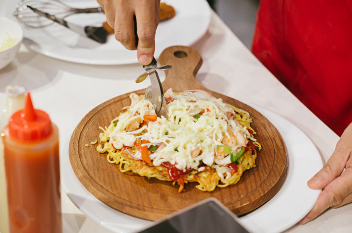 Món ăn độc đáo "Pizza mỳ" sau khi hoàn thành được chính tay ông Hiroharu Motohashi đặt lên đĩa. Món ăn được hoàn thiện, tăng thêm vị ngon bởi chính những sản phẩm gia vị được nghiên cứu, sản xuất bởi chính công ty Ajinomoto.