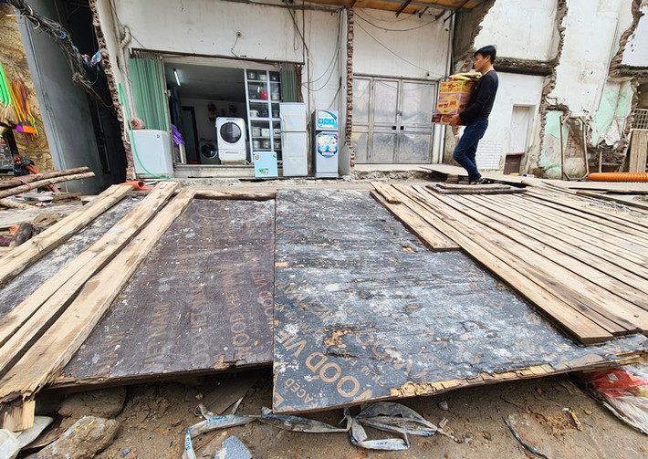 Tuy nhiên, do vỉa hè bị đào xới khoảng hơn một tháng nay để đặt các đường ống buộc nhiều hộ gia đình phải đóng tạm cầu gỗ lấy lối di chuyển vào nhà.