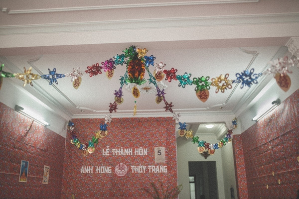 Tường căn phòng nơi diễn ra lễ thành hôn của cặp đôi 8X được dán giấy in hình hoa hồng, hoa mai - họa tiết đặc trưng của những năm 70-80 khiến các vị khách trung niên liên tưởng ngay đến những gì mình đã trải qua trong quá khứ. Do khoảng cách về thời gian nên để tìm được những món đồ trang trí này, cả nhà chú rể đã tốn rất nhiều công sức.