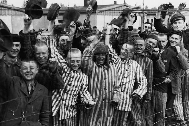 Tù nhân trẻ em trong trại tập trung Dachau vẫy chào binh sĩ Mỹ vào ngày 3/5/1945. Dachau là trại tập trung đầu tiên Adolf Hitler mở tại Đức. Dachau là nguyên mẫu cho các trại tập trung mà Đức Quốc xã xây dựng sau đó. Ảnh: Getty Images.