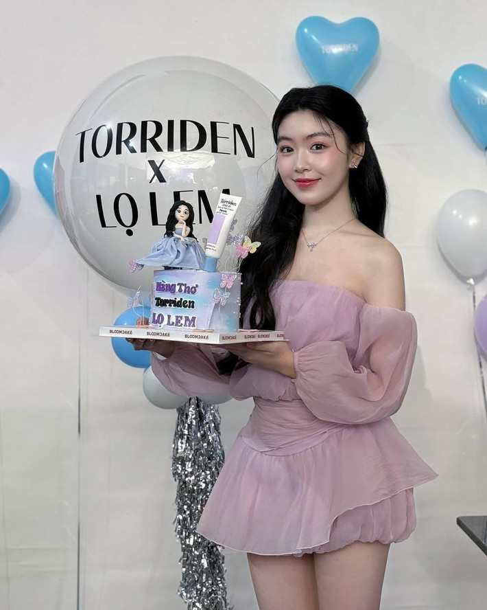 Nụ cười mỉm dịu dàng, e ấp cùng mái tóc dài đen nhánh, được tạo kiểu xoăn nhẹ và điểm xuyết thêm những bông hoa trắng tinh khôi, càng khiến cô bé trông hệt như nàng công chúa bước ra từ câu chuyện cổ tích.