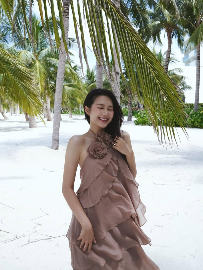 Mái tóc đen dài óng ả buông xõa tự nhiên, vài sợi tóc khẽ bay trong gió, nàng WAG tạo dáng đơn giản, khi thì tựa vào thân cây dừa, lúc lại cười rạng rỡ, đem đến cảm giác thư thái và mềm mại.