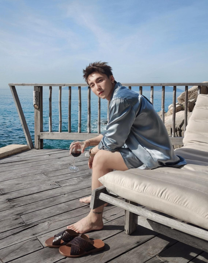 Anh diện set đồ đồng bộ với áo sơ mi lụa mỏng và quần shorts ngắn, kết hợp cùng áo ba lỗ bên trong, tạo nên vẻ ngoài vừa năng động, vừa lãng tử.