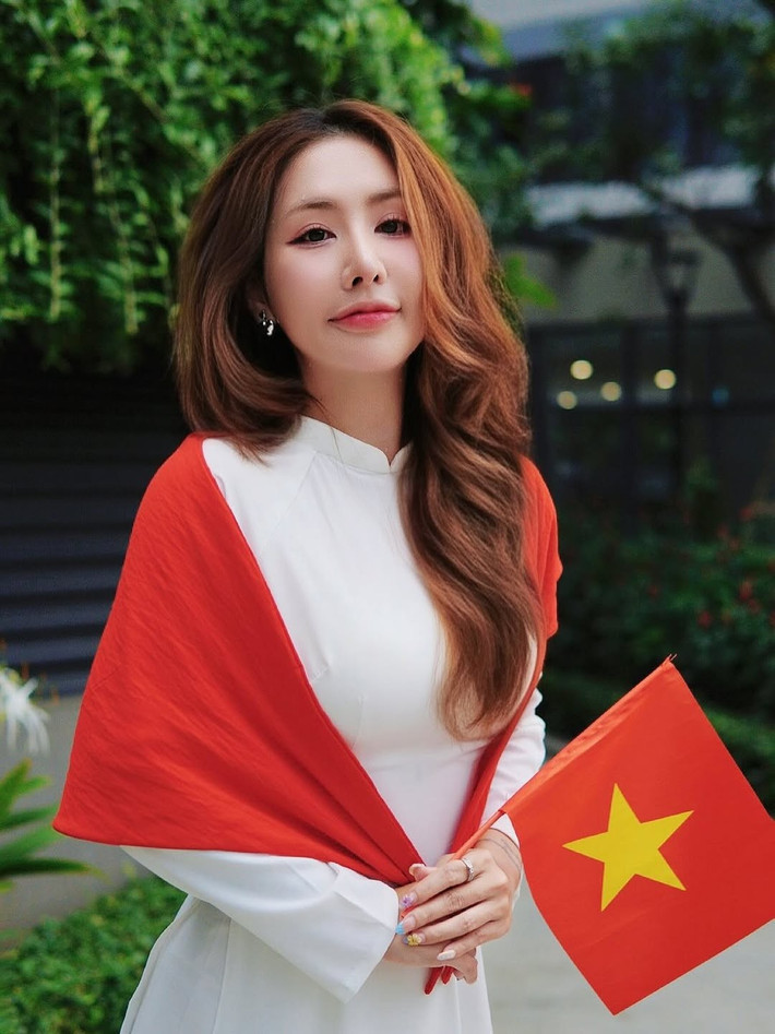 Cô chọn thiết kế áo dài màu trắng tinh khôi, kết hợp với khăn choàng đỏ nổi bật có hình ngôi sao vàng, tái hiện lá cờ Tổ quốc một cách đầy sáng tạo và ý nghĩa. (Ảnh: FBNV)