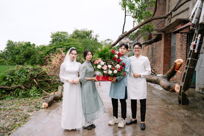 Dù phía sau là khung cảnh đường làng ngổn ngang cây đổ, xe cộ khó khăn trong việc di chuyển, nhưng nụ cười tươi tắn luôn thường trực trên môi cặp đôi.