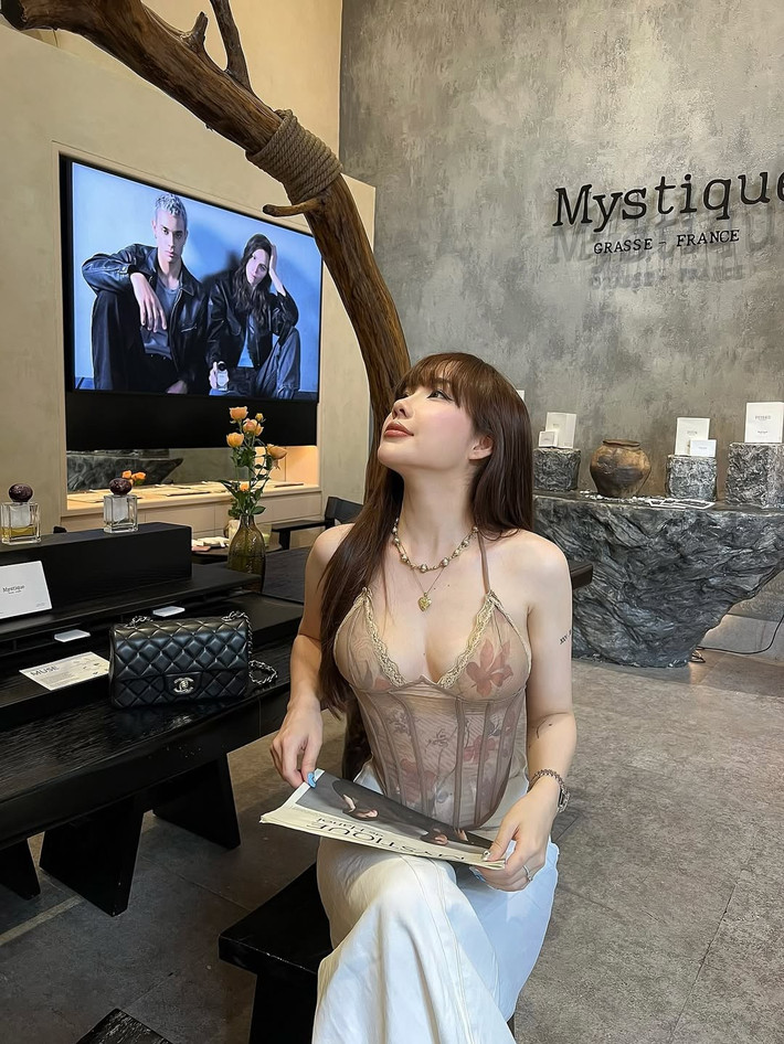 Bối cảnh được chọn là một quán cà phê mang phong cách tối giản, sử dụng nhiều chất liệu đá và gỗ thô, càng làm nổi bật vẻ nữ tính và mềm mại của nhân vật chính.