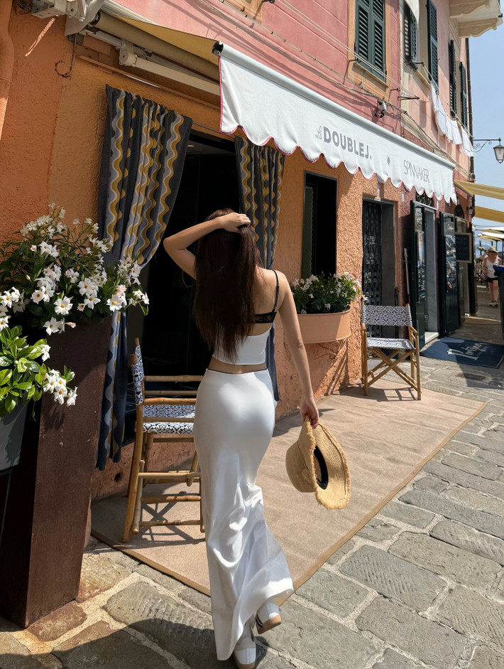 Cô tự tin tạo dáng khi thì đứng từ trên cao, khi thì đi dạo, với phông nền là khung cảnh Portofino đẹp như tranh vẽ: những ngôi nhà nhiều màu sắc nằm san sát bên bờ biển xanh ngắt, với bến cảng tấp nập thuyền bè và những ngọn đồi xanh mướt bao quanh.