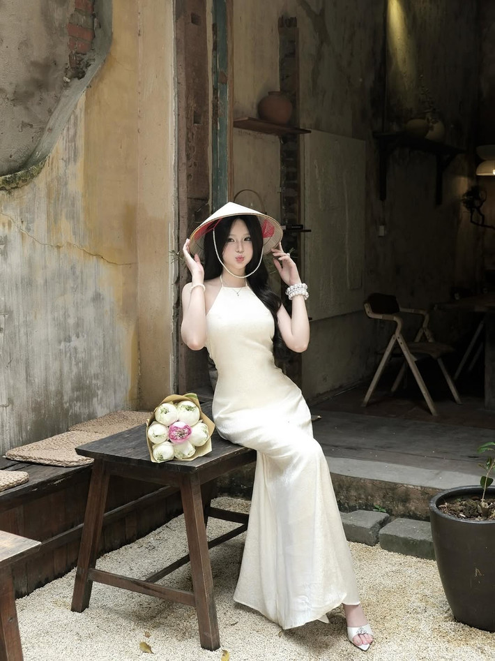 Đặc biệt, bó hoa sen trắng e ấp, biểu tượng của sự thanh khiết và tinh thần Việt Nam, được cô ôm nhẹ nhàng, càng làm tăng thêm vẻ đẹp dịu dàng, thoát tục. (Ảnh: IGNV)