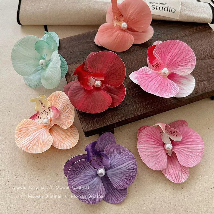 Những mẫu kẹp hoa sứ, hoa lan vốn đã "làm mưa làm gió" những mùa hè năm trước thì năm nay vẫn chưa hề hết hot. Những thiết kế hoa với đủ màu sắc giúp chị em hoàn thiện set đồ, có những tấm ảnh sống ảo đậm chất "nàng thơ".
