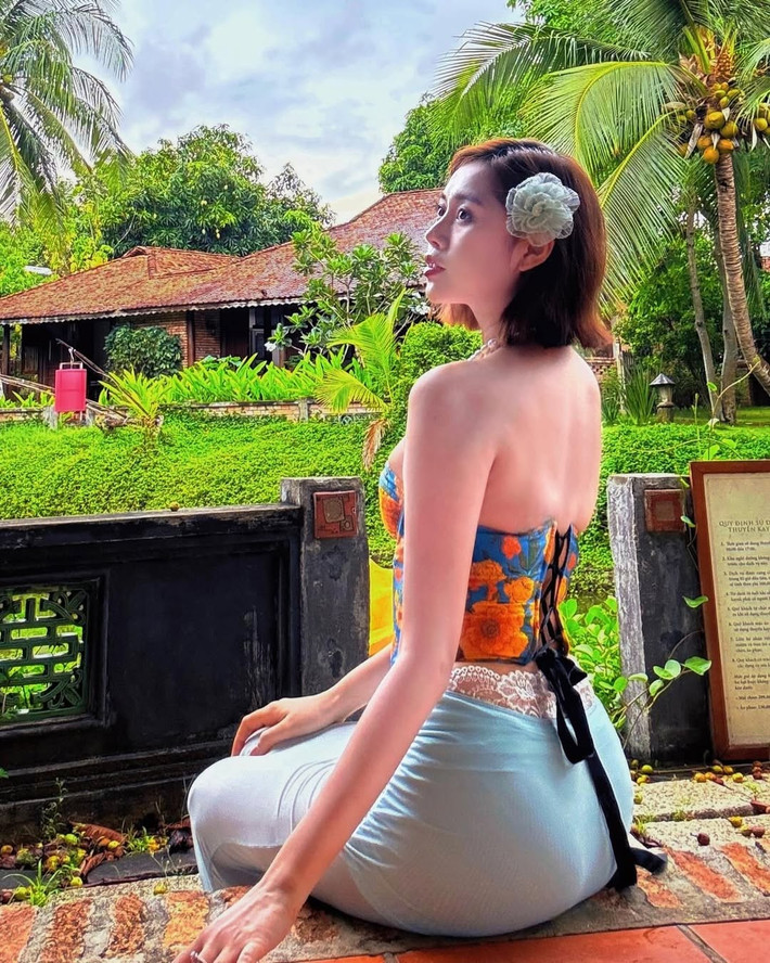 Cô nàng kết hợp cùng áo corset là chiếc chân váy lụa ôm sát, chất liệu nhẹ nhàng, bay bổng giúp tôn dáng mà vẫn giữ được sự thanh lịch. Lớp vải xuyên thấu ở phần eo được cài thêm dây ren và hoa giả, tạo hiệu ứng thị giác bắt mắt, nhấn nhá cho tổng thể thêm phần quyến rũ.