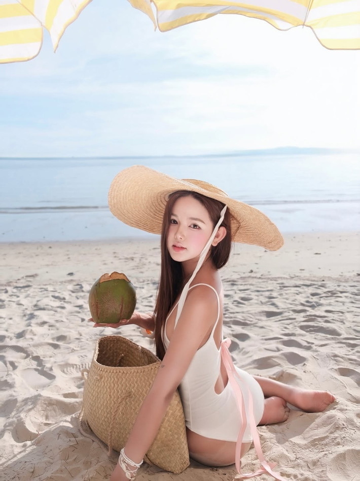Trong một khoảnh khắc thư giãn trên bãi cát trắng, Thư Thỏ hóa thân thành nàng thơ dịu dàng với bộ bikini liền thân màu trắng tinh khôi. Thiết kế đơn giản nhưng tinh tế với điểm nhấn là những dải ruy băng màu hồng pastel nhẹ nhàng ở phần lưng, tạo cảm giác thanh thoát và đáng yêu.