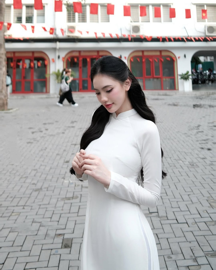 Chiếc áo dài, vốn là biểu tượng của người phụ nữ Việt Nam, càng làm nổi bật vẻ đẹp dịu dàng, e ấp nhưng cũng không kém phần hiện đại của cô gái.