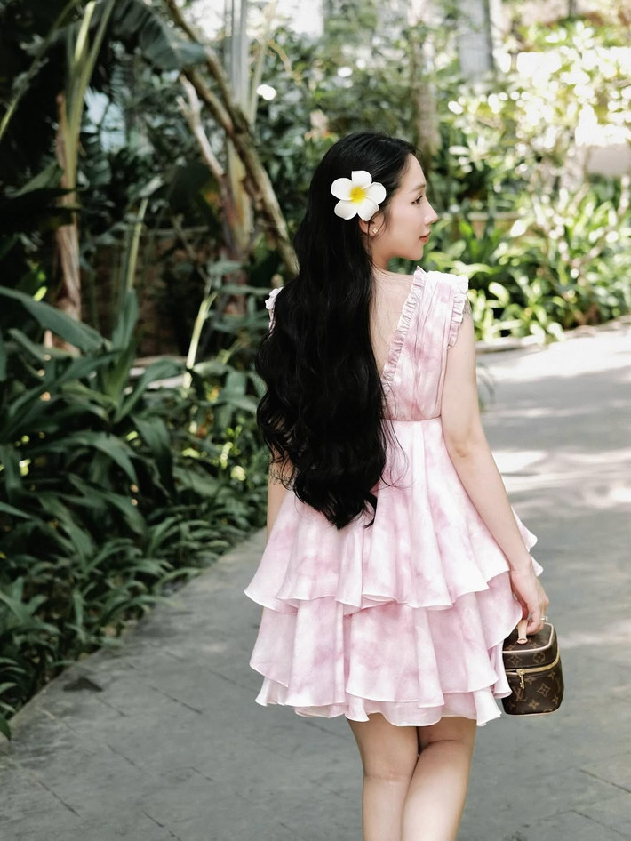 Một chiếc váy hồng pastel xếp tầng điệu đà, kết hợp với túi xách nhỏ xinh tạo nên vẻ ngoài ngọt ngào, nữ tính.