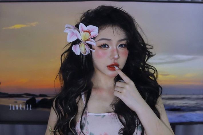 Nàng hot girl áp dụng lối trang điểm đậm chất "Tây", với lớp nền trắng sáng, đôi mắt to tròn được nhấn nhá kỹ lưỡng bằng lens và eyeliner sắc sảo. Đặc biệt là phần má hồng đánh cao và đậm, tạo hiệu ứng say nắng, cùng đôi môi đỏ mọng quyến rũ. Lối trang điểm này mang lại vẻ đẹp vừa hiện đại, vừa có chút bí ẩn, khác lạ.