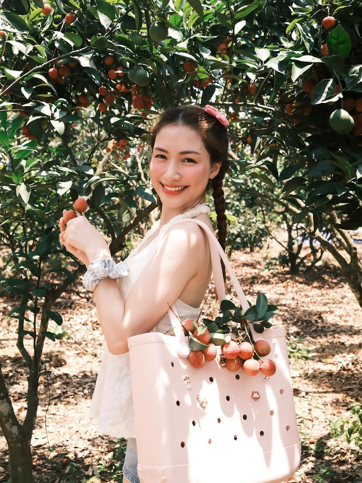 Mái tóc dài được tết hai bên gọn gàng, tô điểm thêm chiếc kẹp tóc hình nơ màu hồng và chiếc scrunchie xinh xắn, càng làm tăng thêm nét trẻ trung, đáng yêu.