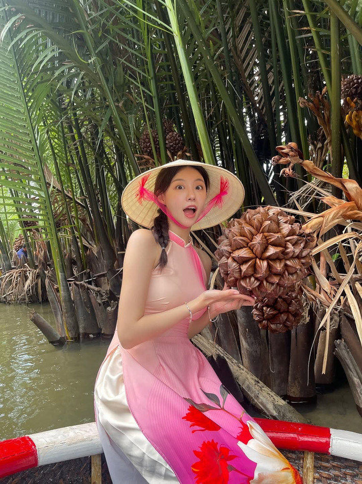 Cô diện chiếc áo dài được thiết kế cách điệu với phần cổ yếm màu hồng nhạt, ôm sát cơ thể với phần tà in họa tiết hoa lớn nổi bật. Chiếc áo dài này không chỉ tôn lên vóc dáng thanh thoát mà còn làm nổi bật vẻ dịu dàng, nữ tính của cô. (Ảnh: IGNV)